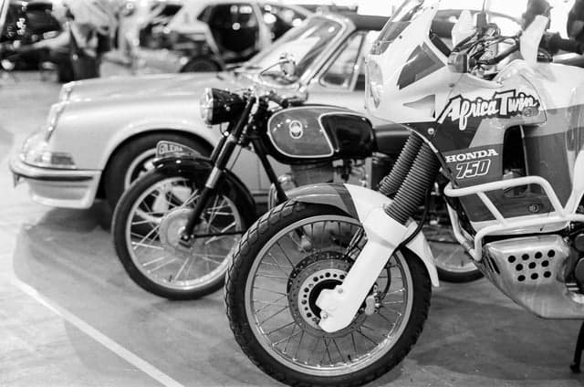 Motorcycles and a classic car in a monochrome photograph